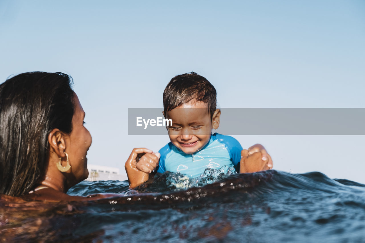 Portrait of a young mother and son playing at sea