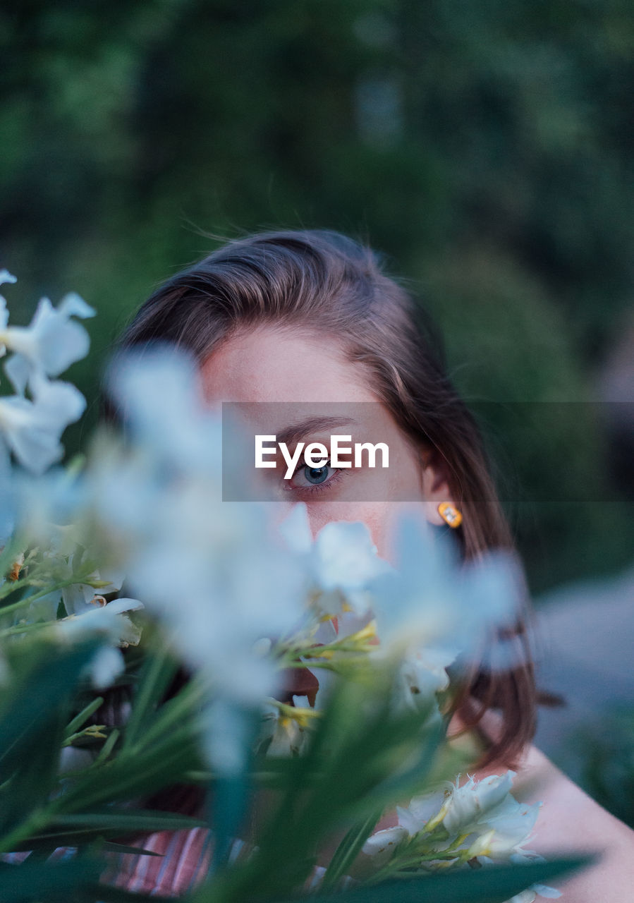 Portrait of woman behind flowering plant