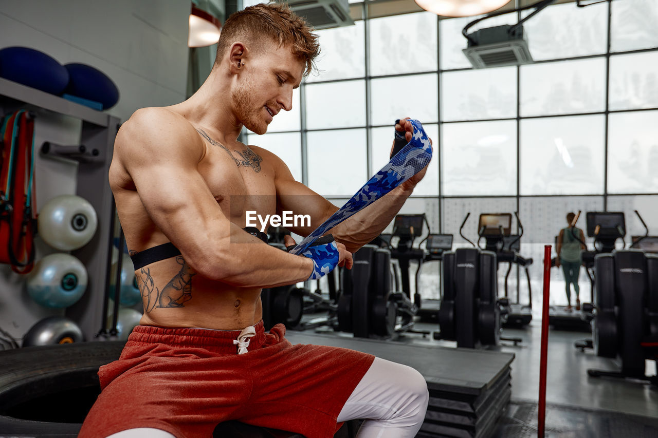 portrait of shirtless man exercising in gym