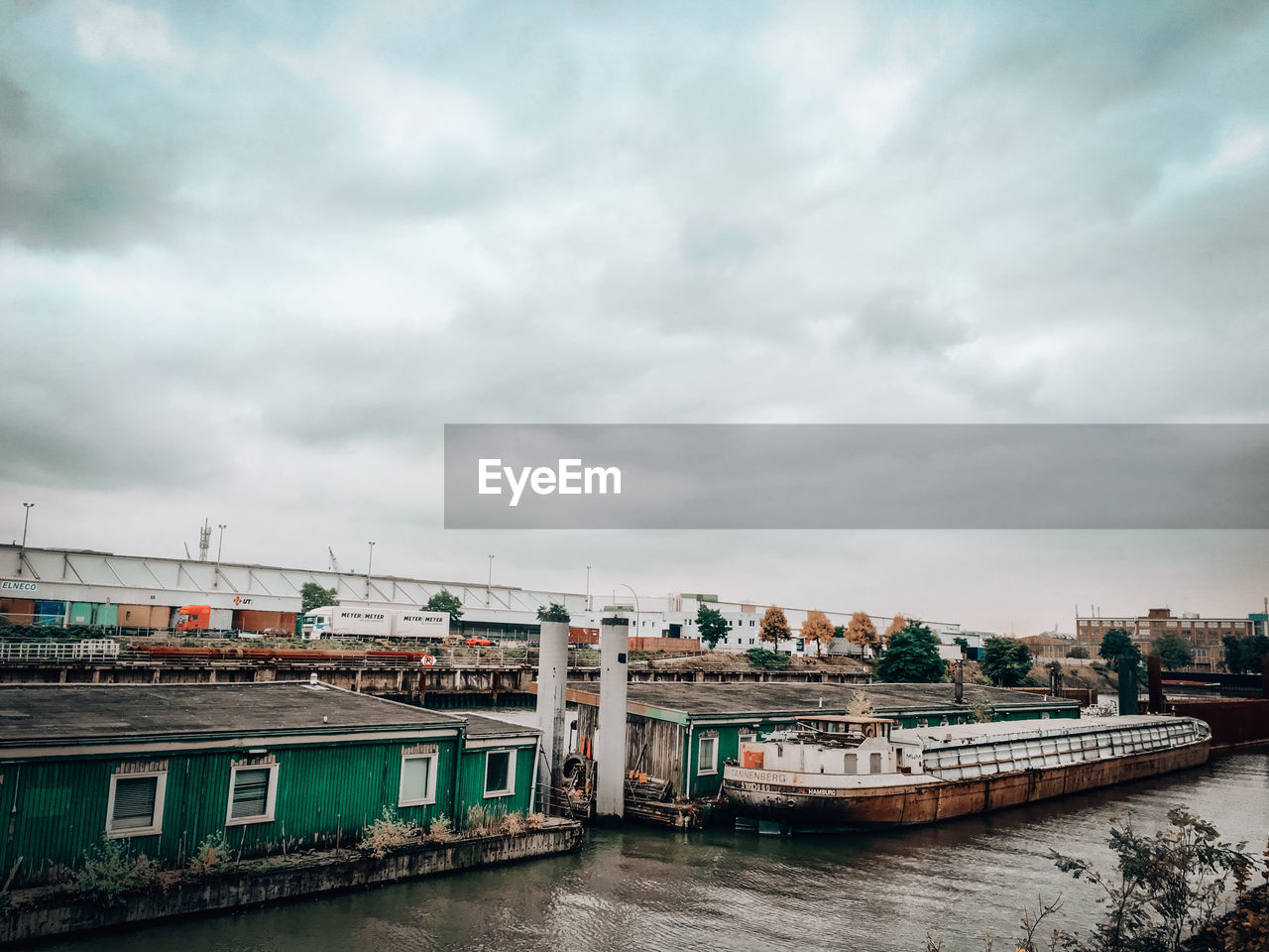 Buildings by river against sky in city