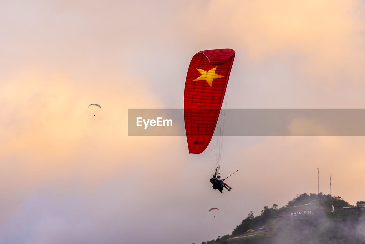 adventure, flying, extreme sports, sky, mid-air, sports, sunset, paragliding, transportation, nature, environment, windsports, leisure activity, joy, parachute, air sports, landscape, exhilaration, cloud, motion, silhouette, dramatic sky, outdoor pursuit, activity, beauty in nature, air vehicle, gliding, recreation, safety harness, mountain, multi colored, sports equipment, pilot, outdoors, wind, scenics - nature, parachuting, sign, lifestyles, vibrant color, fly, red, travel destinations, one person, land, risk, warning sign, mode of transportation, moody sky, vacation, holiday, protection, dusk, trip, emotion, travel, full length, fog, sun, communication, fun, piloting, orange color, jumping