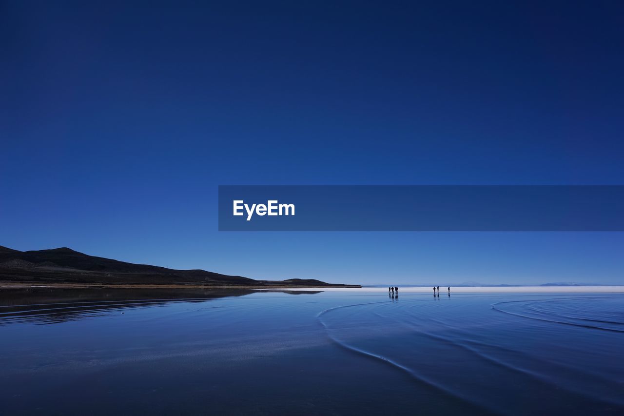 Scenic view of lake against clear blue sky