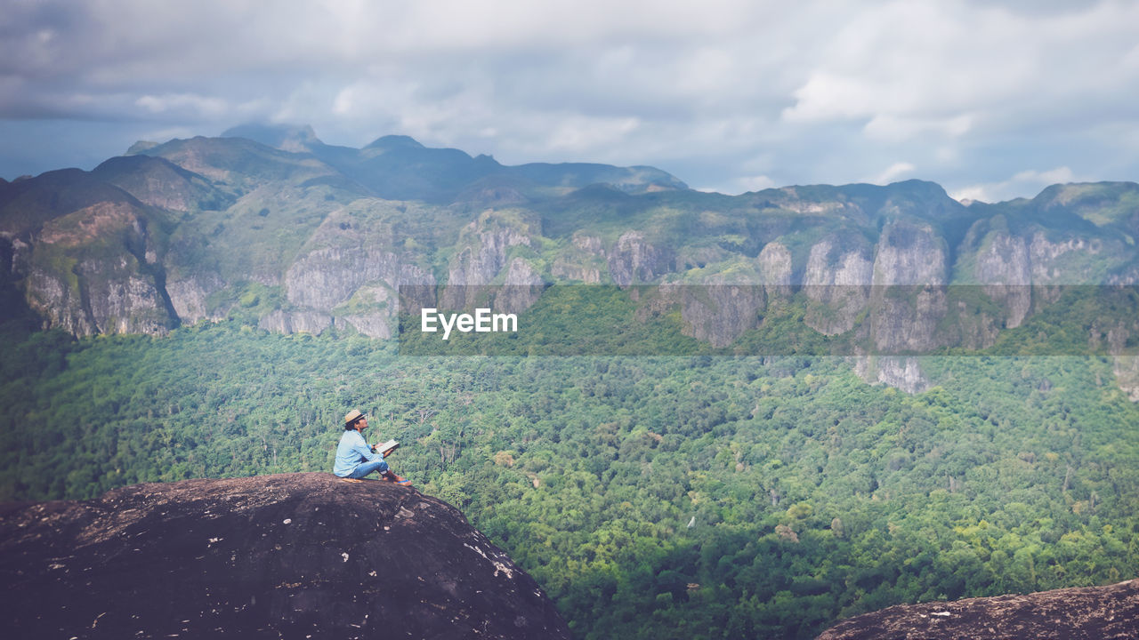 rear view of man sitting on rock