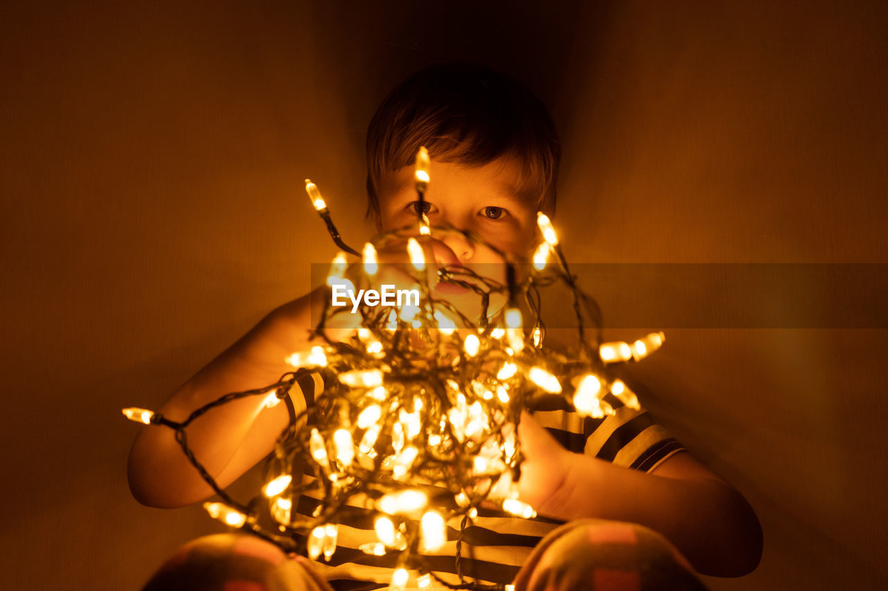 Full length of boy with illuminated lights at home
