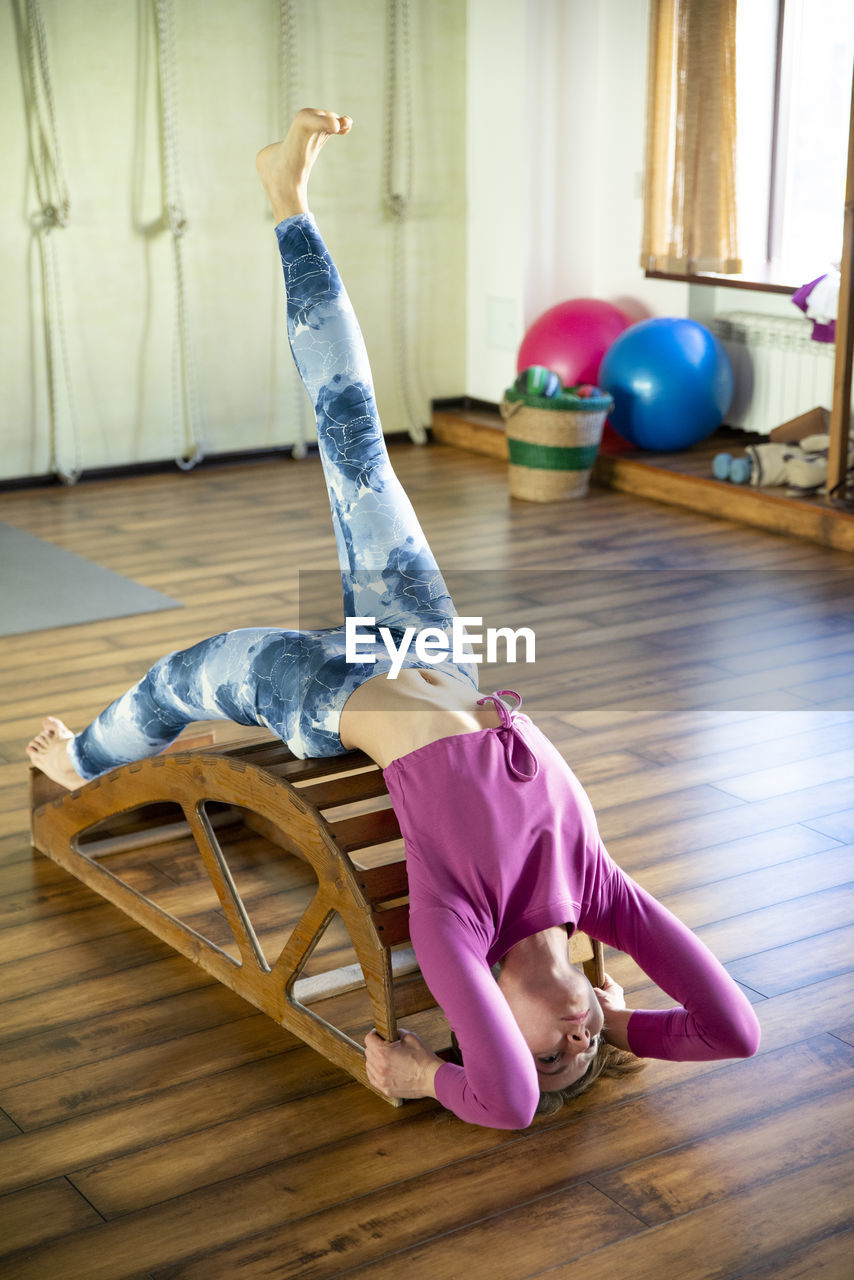 Full length of woman lying on hardwood floor at home