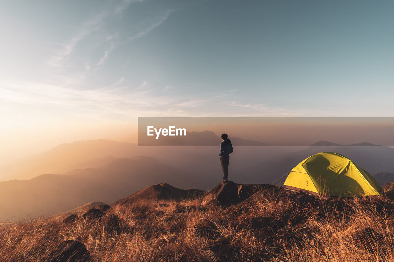 Man standing on mountain against sky during sunrise