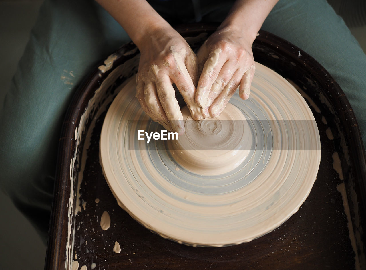 Woman starts to create a ceramic cup on the pottery wheel. working with clay on potter's wheel.