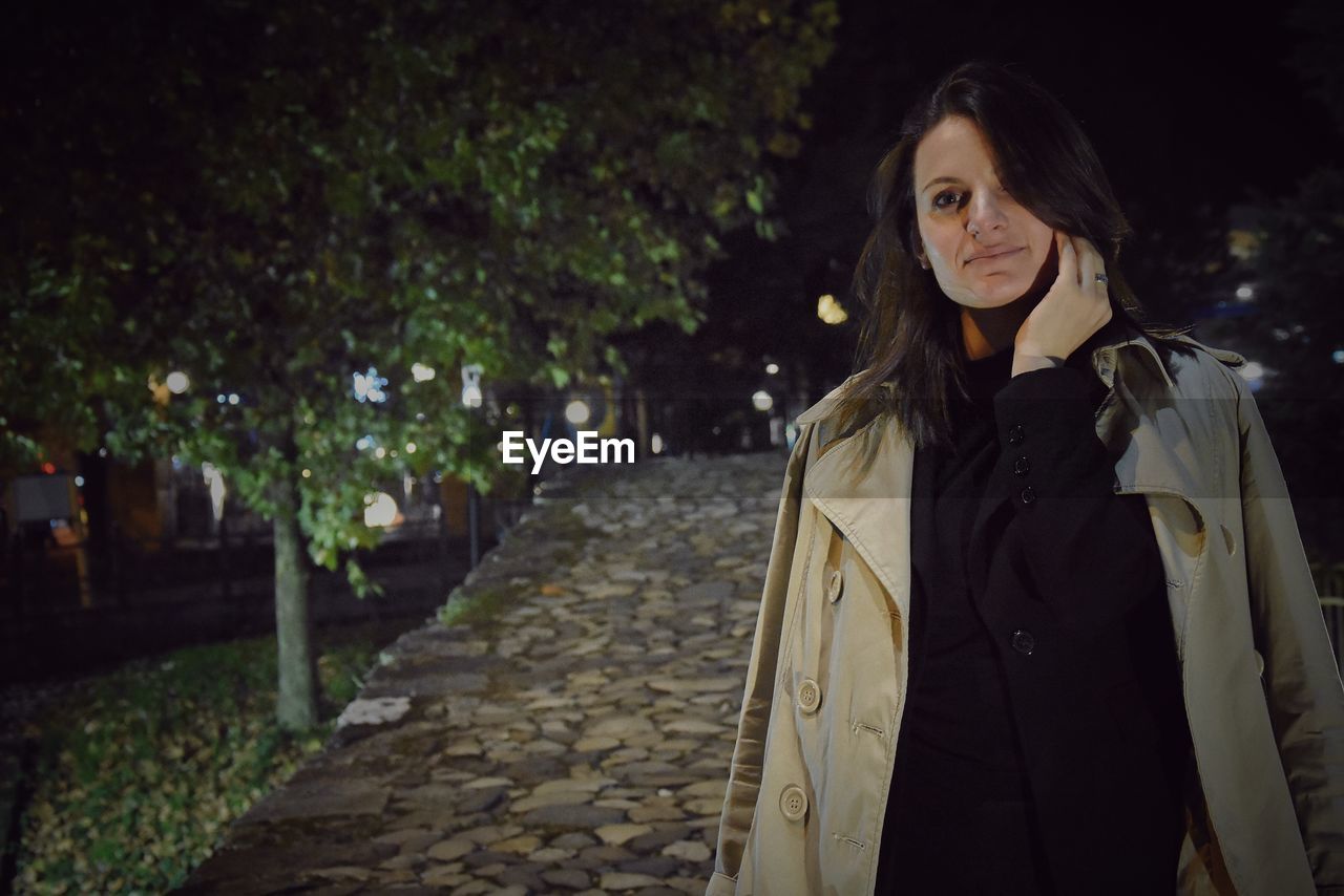 Portrait of woman standing on street at night