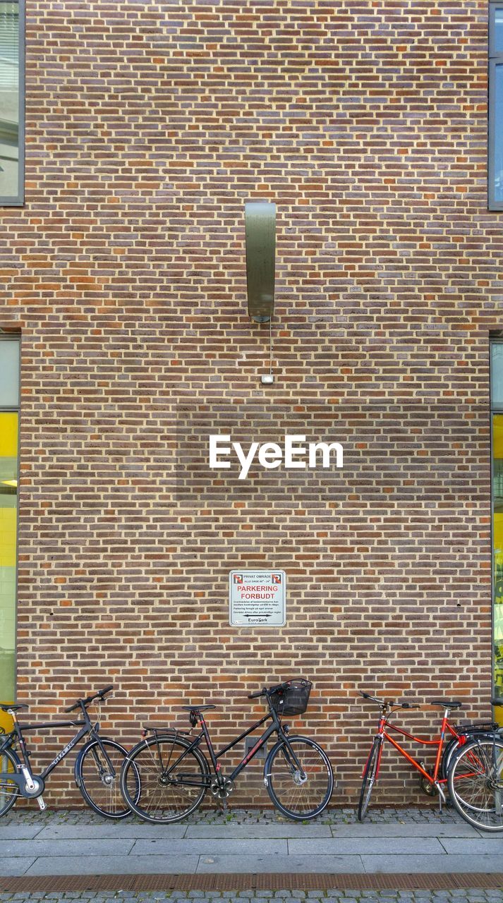 Bicycles parked by brick wall