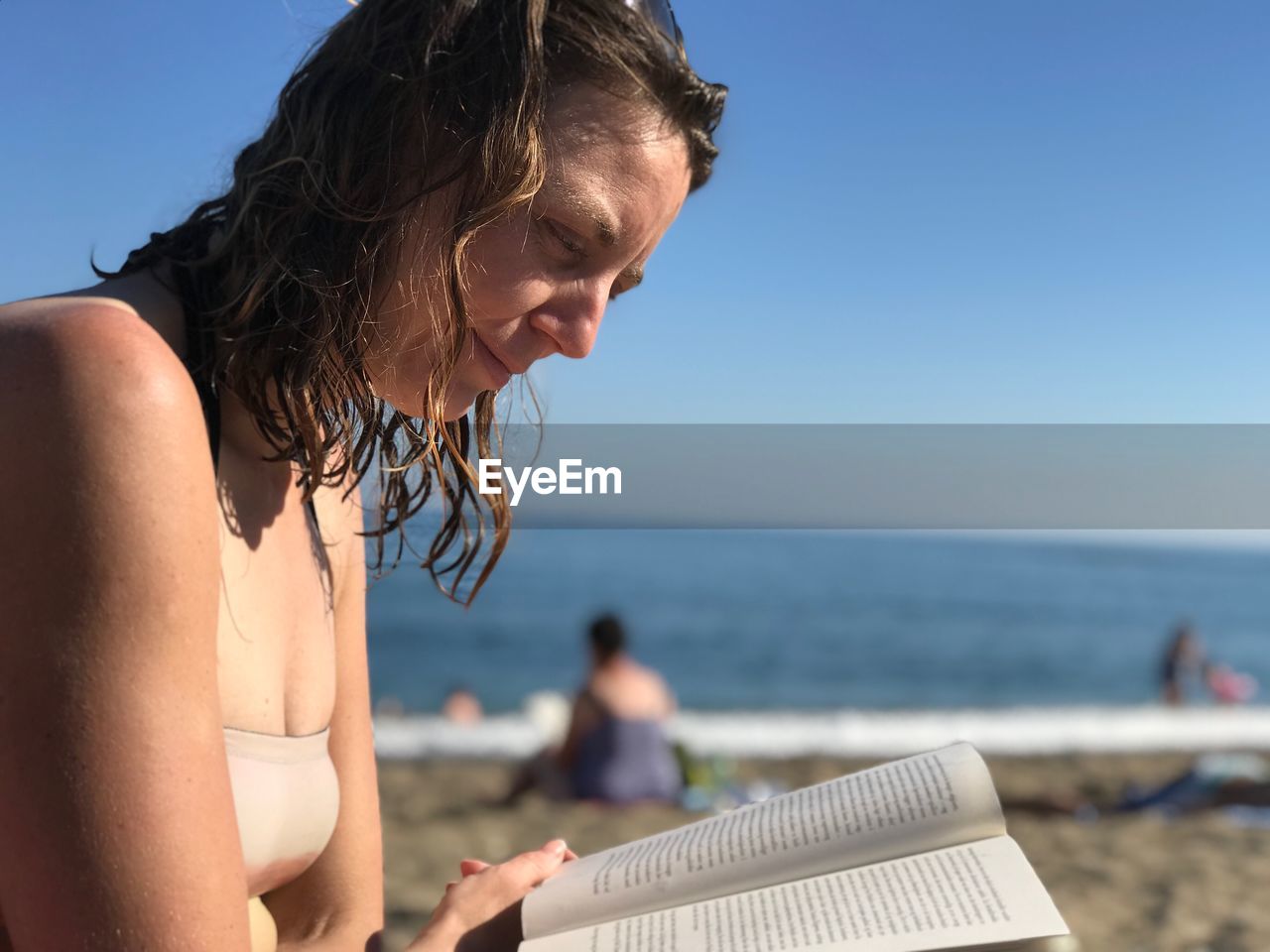 Close-up of woman reading book at beach