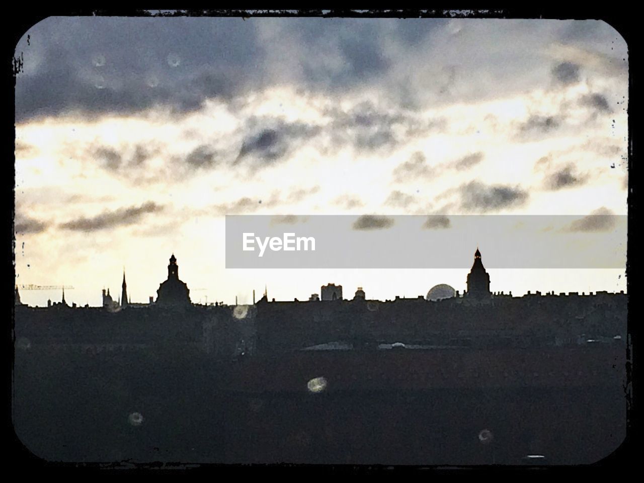 LOW ANGLE VIEW OF BUILDINGS AGAINST CLOUDY SKY AT SUNSET