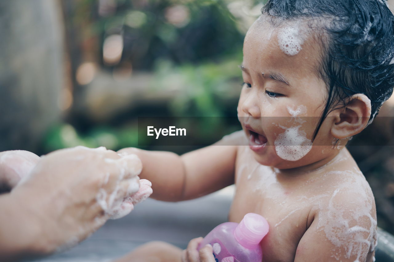 Cropped image of parent bathing cute baby girl