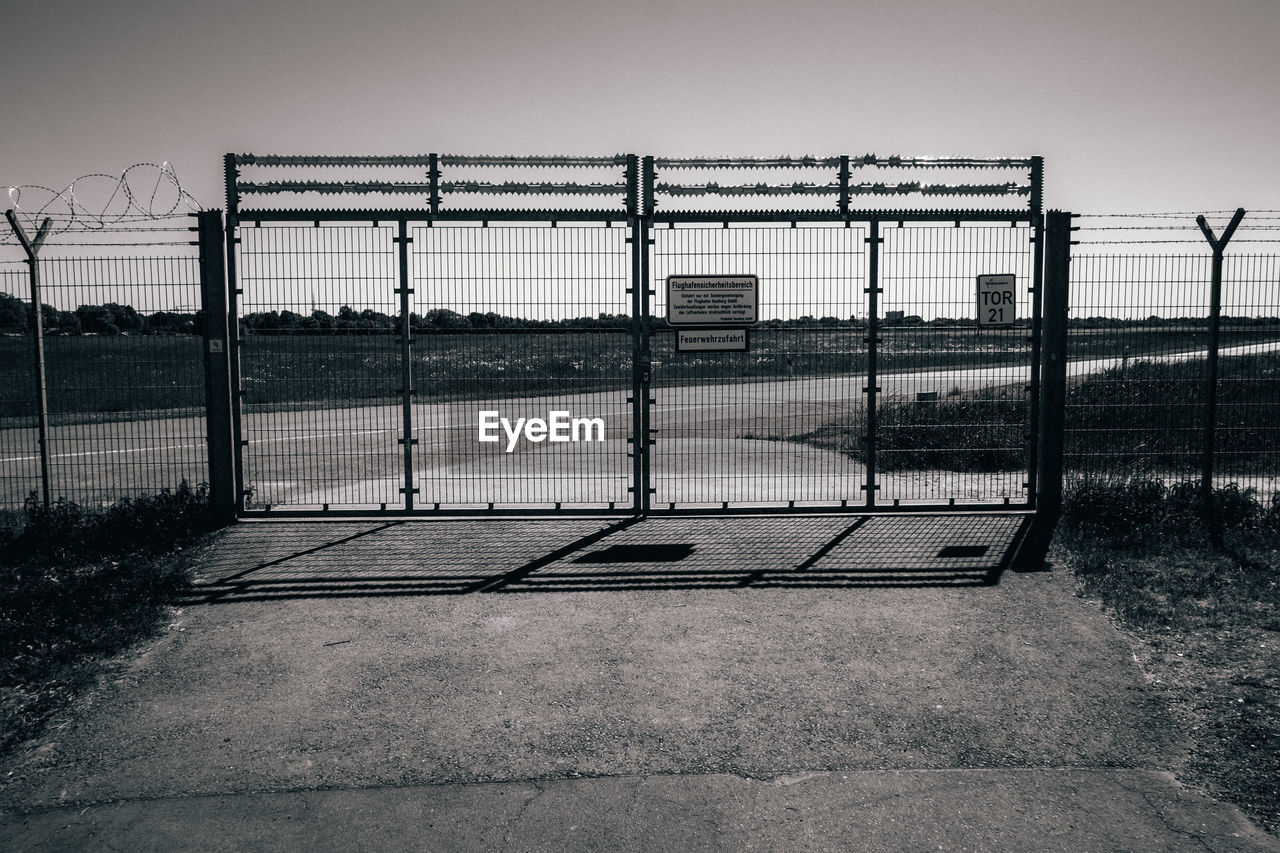 CHAINLINK FENCE ON FIELD AGAINST SKY