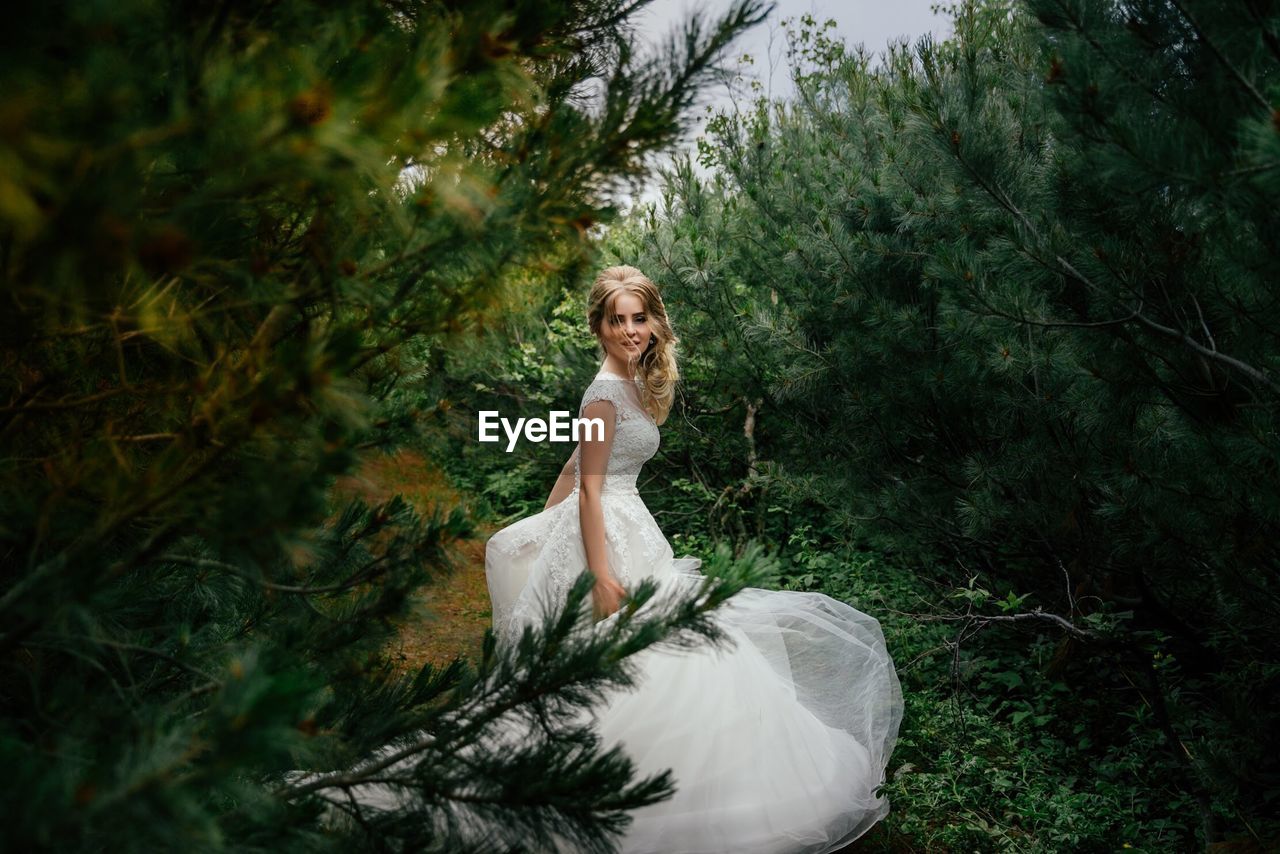 PORTRAIT OF YOUNG WOMAN IN FOREST AGAINST TREES