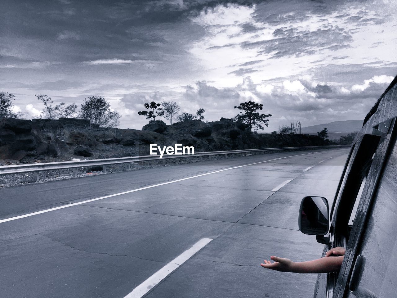 Cropped image of child putting hand out of car window during rainy season