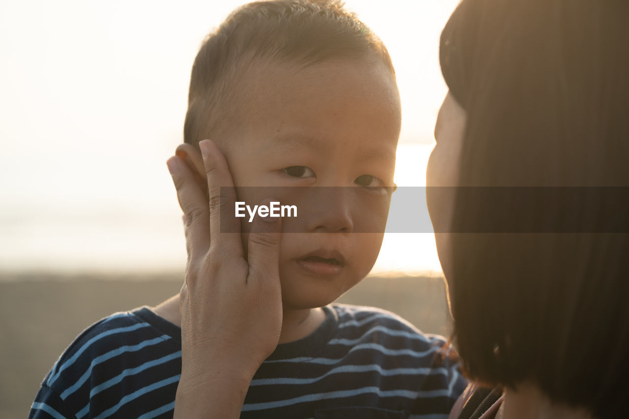 CLOSE-UP PORTRAIT OF CUTE BOY AND SON AGAINST SKY