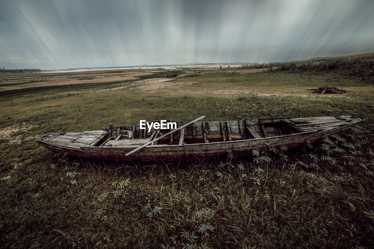Abandoned boat moored on land against sky
