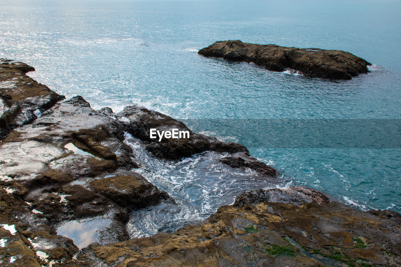 HIGH ANGLE VIEW OF ROCKS ON SEA