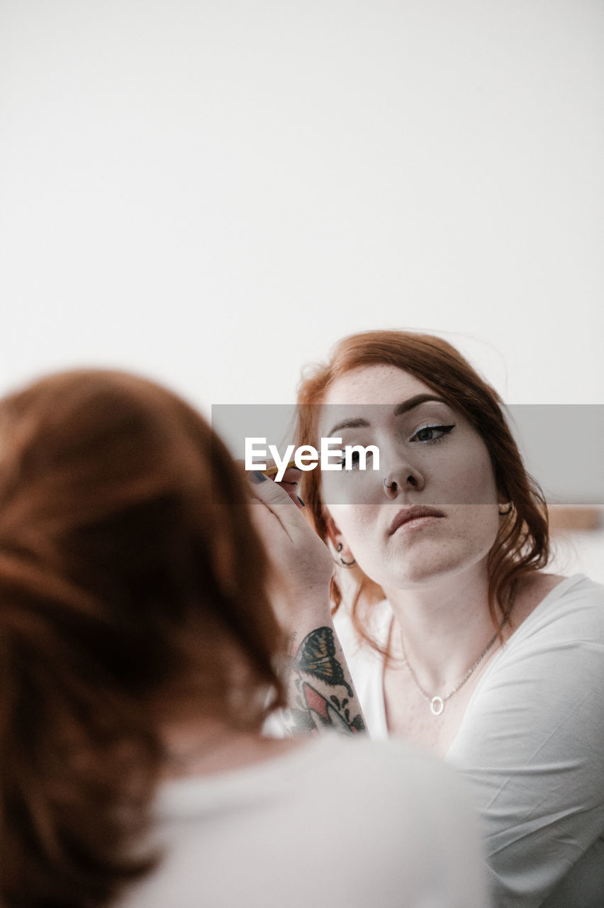 Young woman applying make-up at home