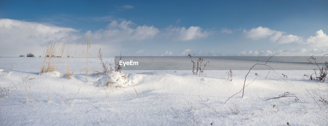 Panoramic view of snow covered field against sky