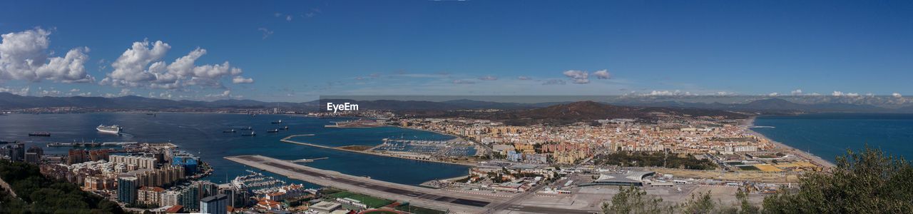 HIGH ANGLE VIEW OF SEA AND BUILDINGS AGAINST SKY