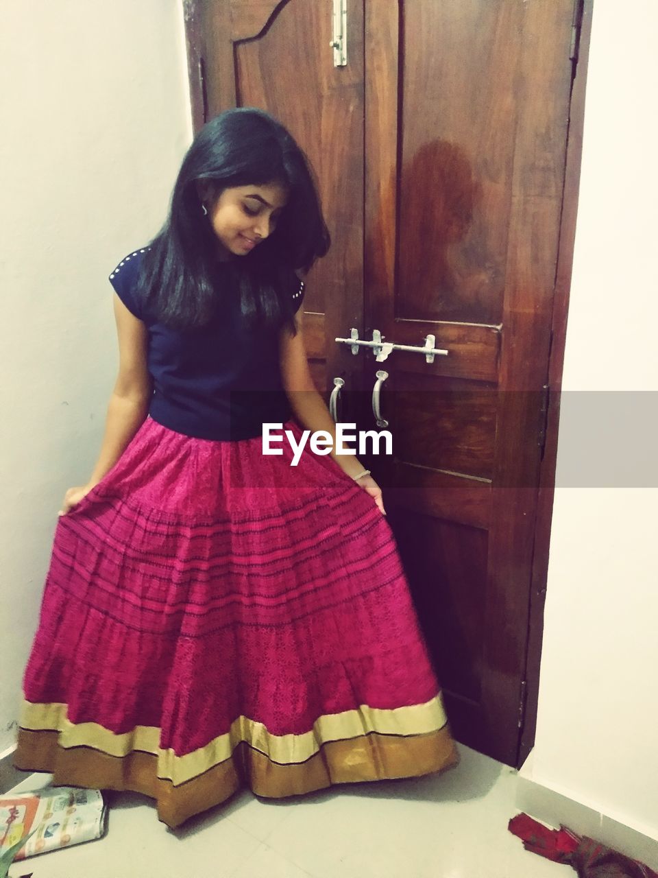 PORTRAIT OF BEAUTIFUL YOUNG WOMAN STANDING AT ENTRANCE OF BUILDING