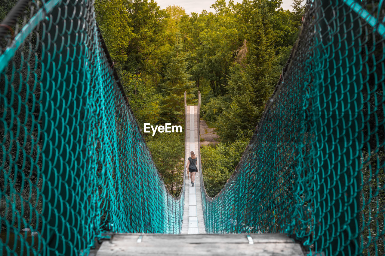 Rear view of woman walking on pinawa suspension bridge