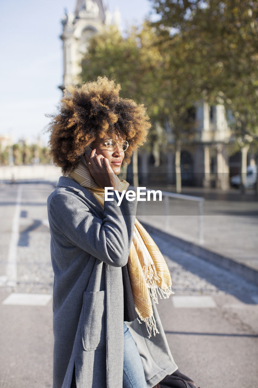 Woman talking on mobile phone while standing on city street