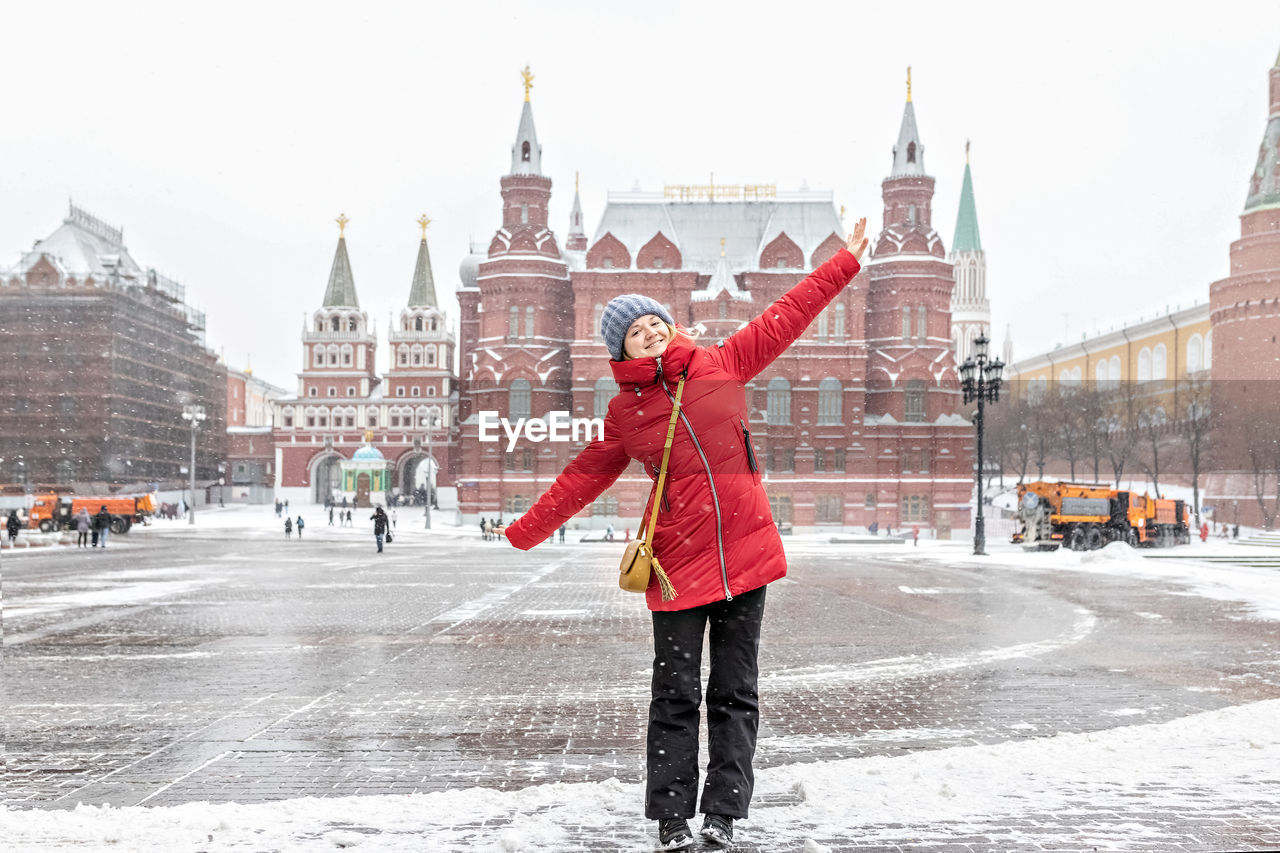 WOMAN STANDING ON SNOW COVERED CITY IN WINTER