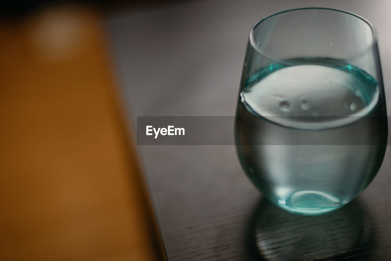 Opaque glass filled with water resting on table.