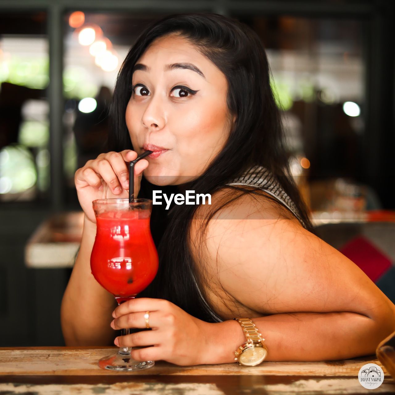 Portrait of young woman drinking red drink in cafe