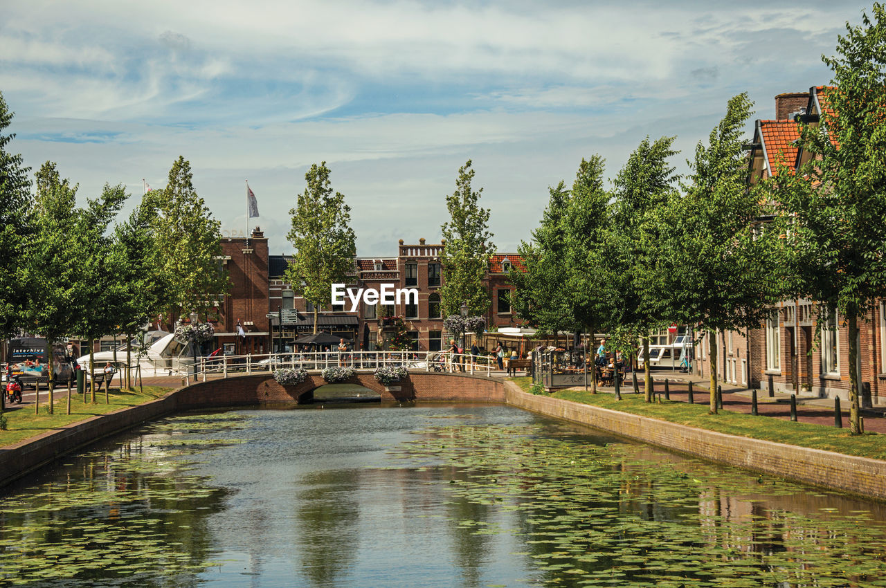 Canal with streets on the banks and brick houses in weesp. a pleasant small village in netherlands.