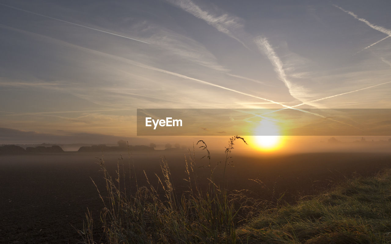 Scenic view of vapor trails in sky during sunset