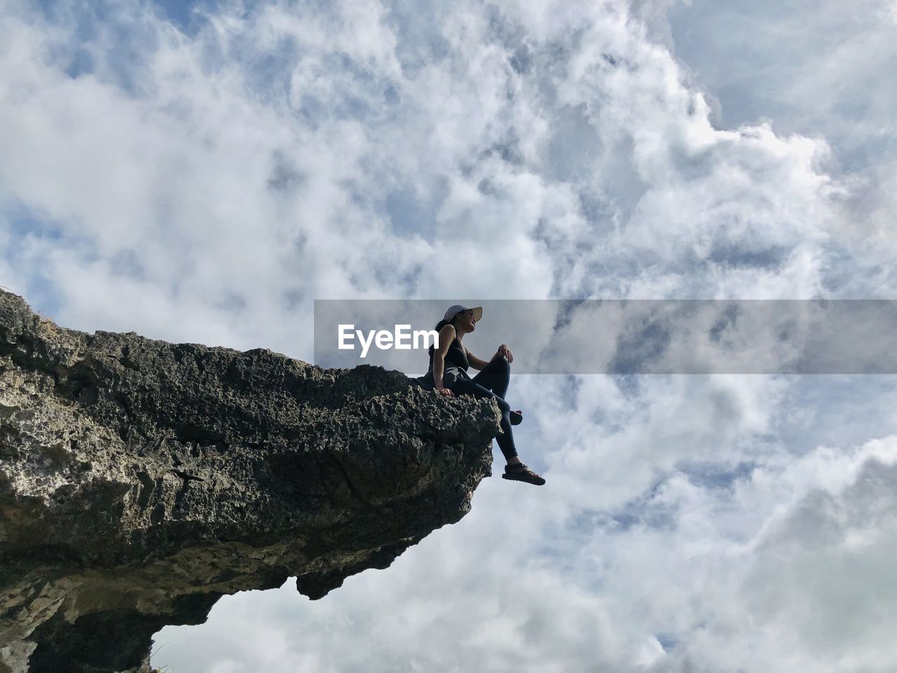 Low angle view of people on rock against sky