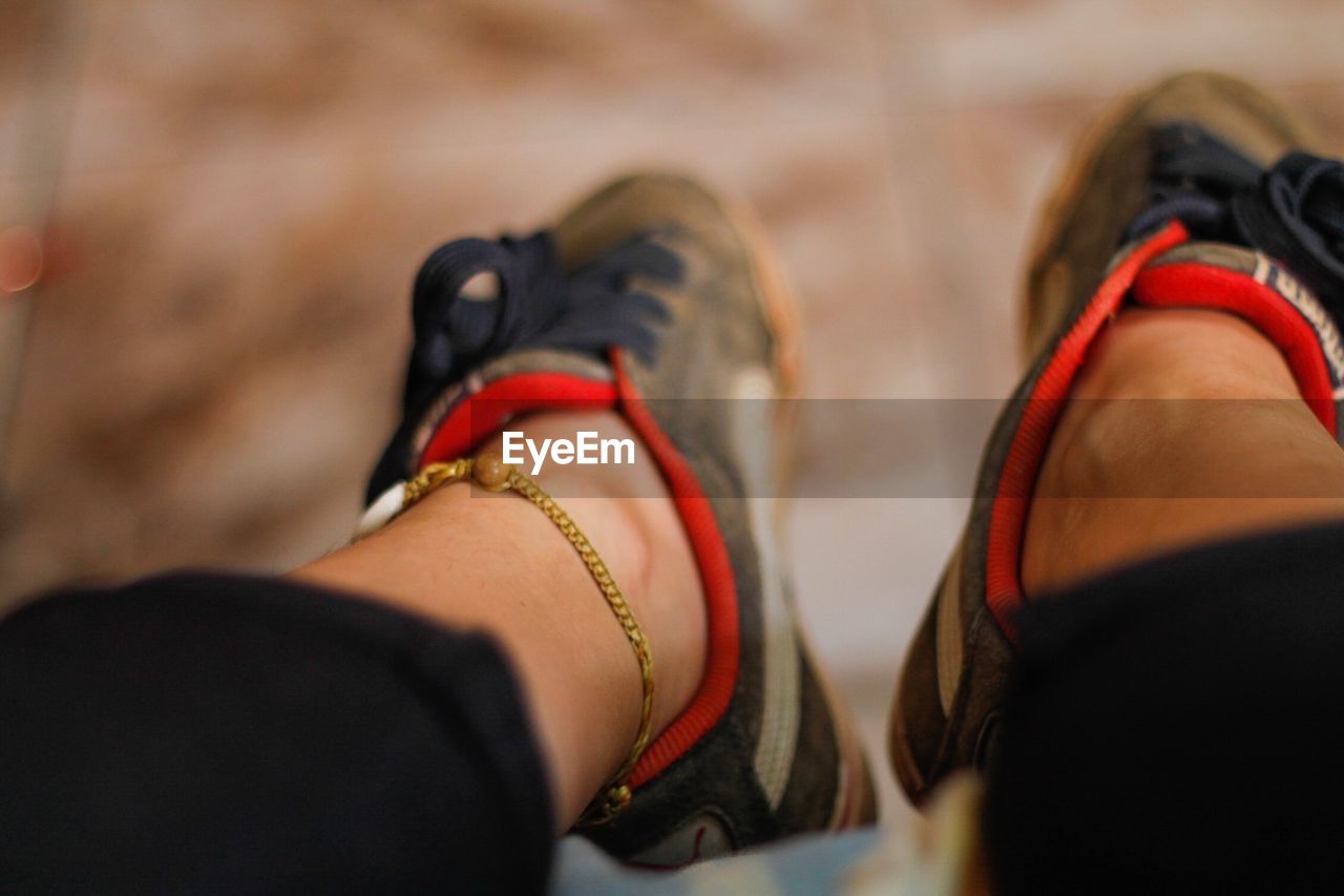 LOW SECTION OF WOMAN WEARING SHOES ON FLOOR