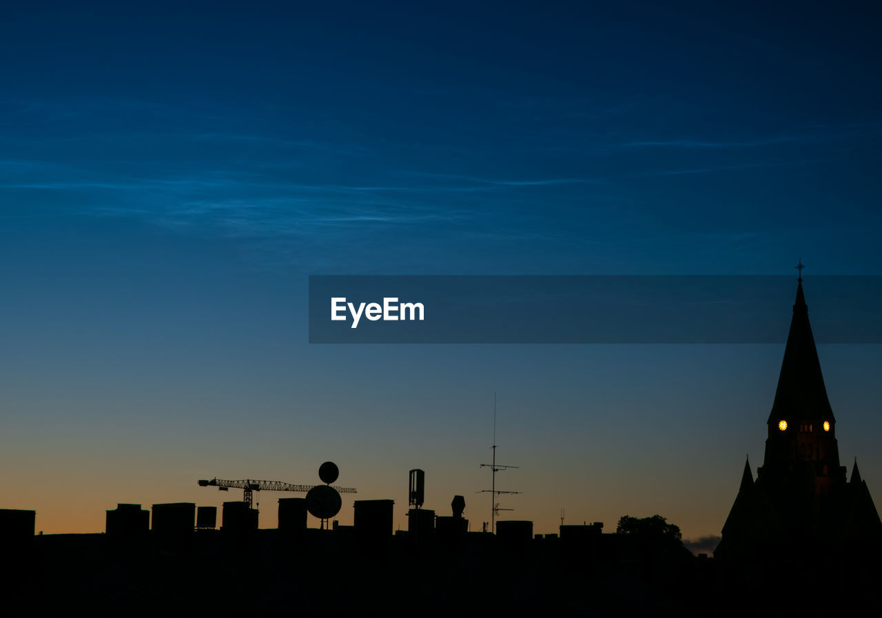 Silhouette of buildings against sky with noctilucent clouds during sunset