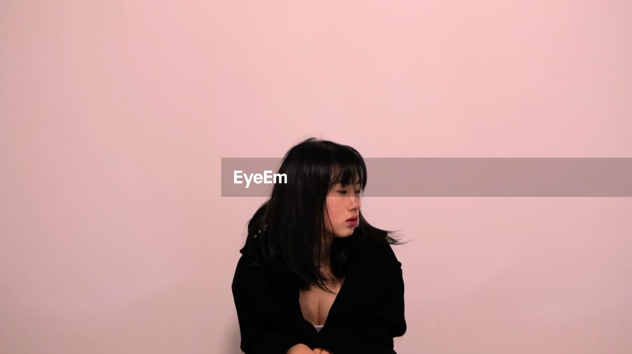 Sad young woman against pink background