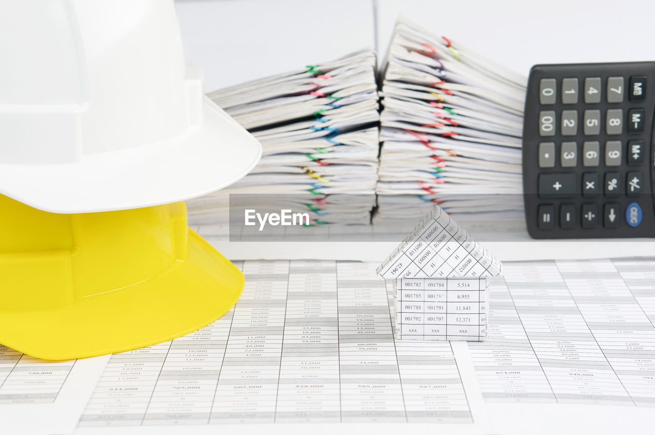 Close-up of hardhat by paperwork stacked on table