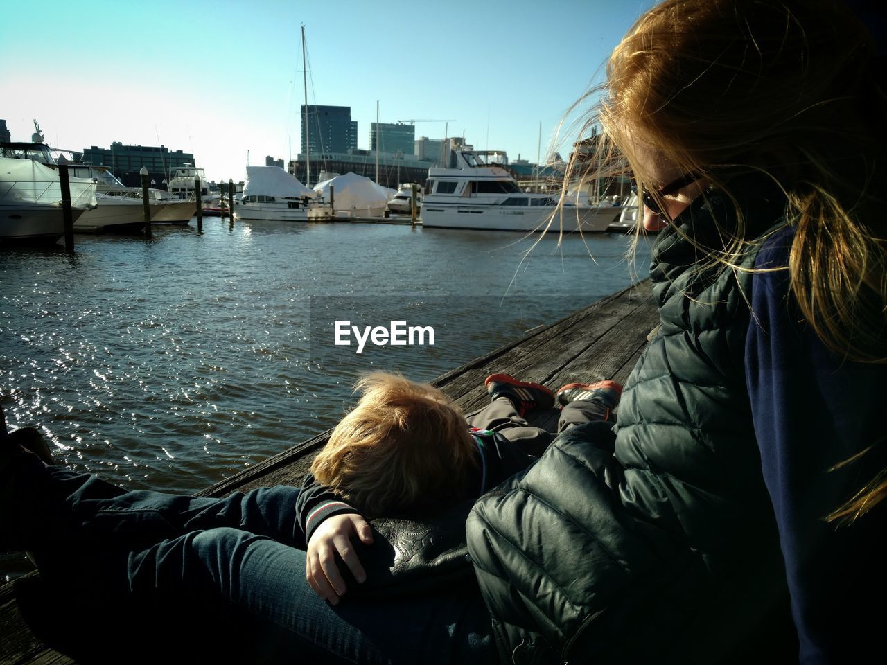 Full length of mother and son relaxing at harbor in city