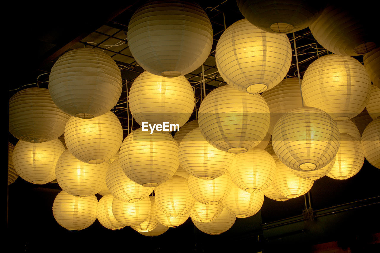 LOW ANGLE VIEW OF ILLUMINATED LANTERNS HANGING AT CEILING