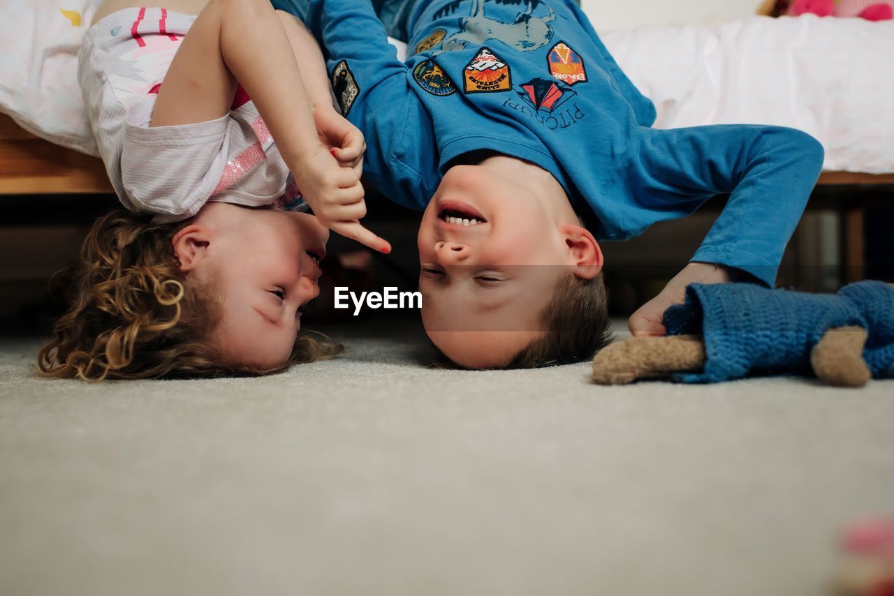 Brother and sister laughing playing in bedroom. siblings having fun