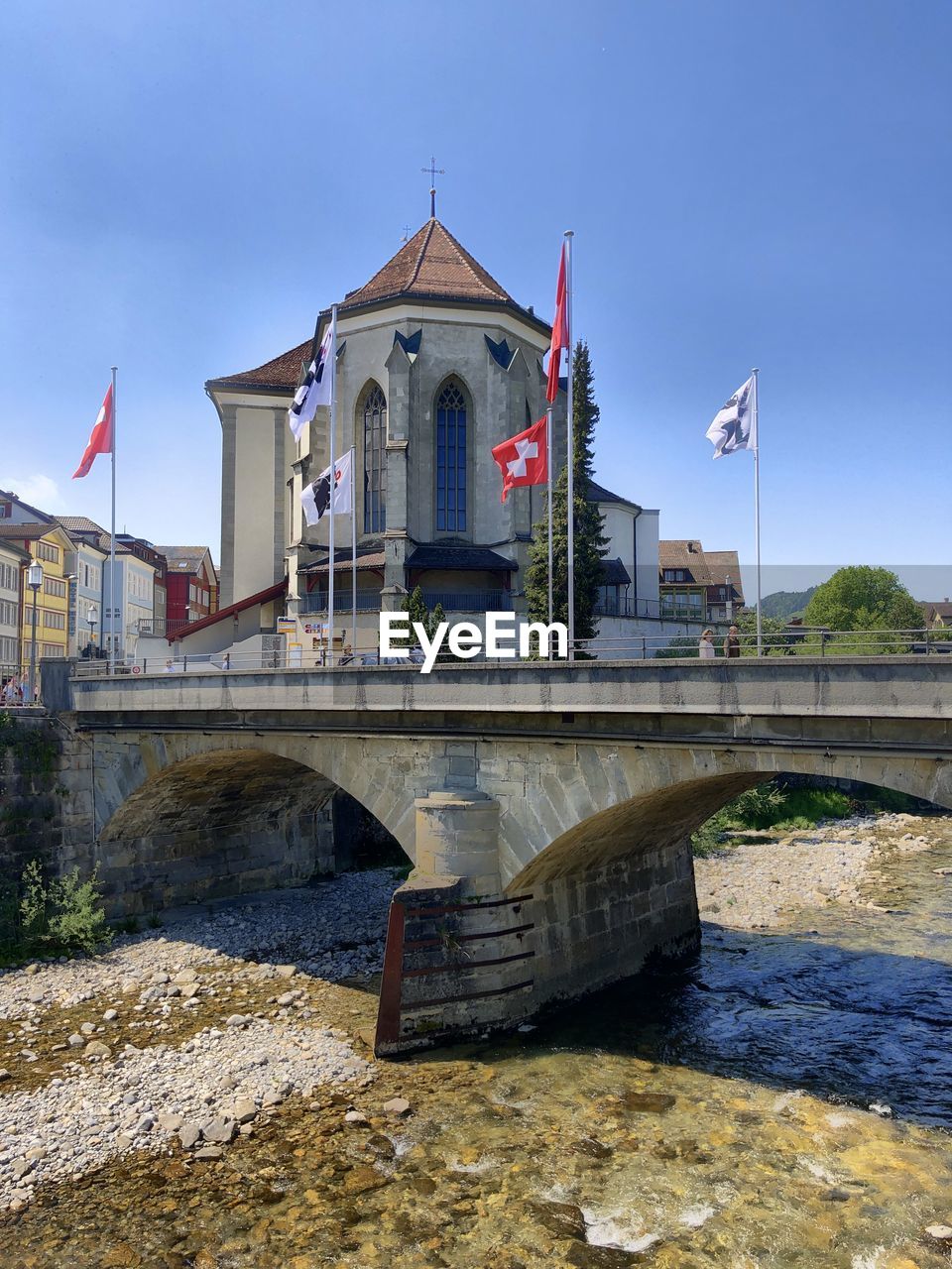 Bridge over river by building against sky