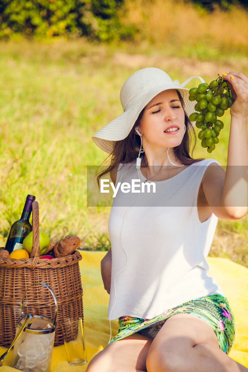 Young woman holding grapes while sitting outdoors