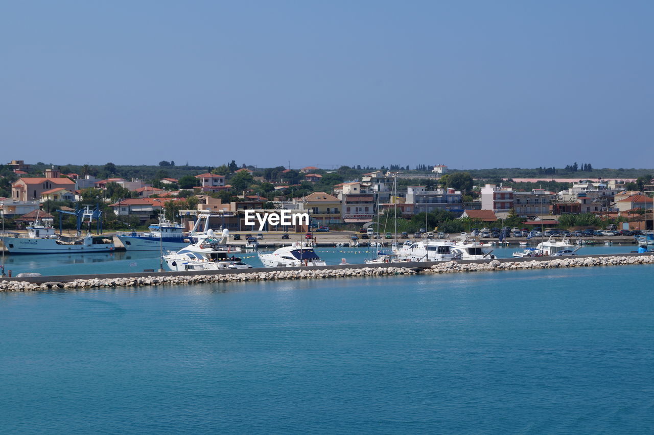 Town by sea against clear blue sky