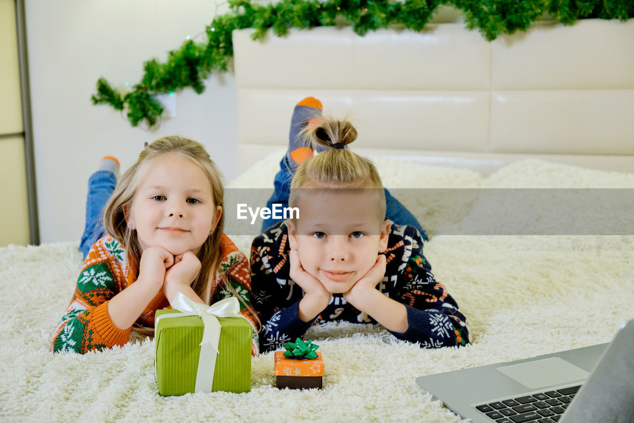 Siblings lying on bed at home