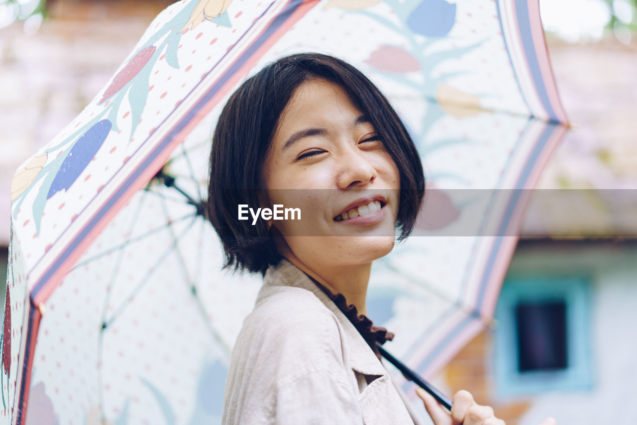 PORTRAIT OF SMILING WOMAN IN RAIN