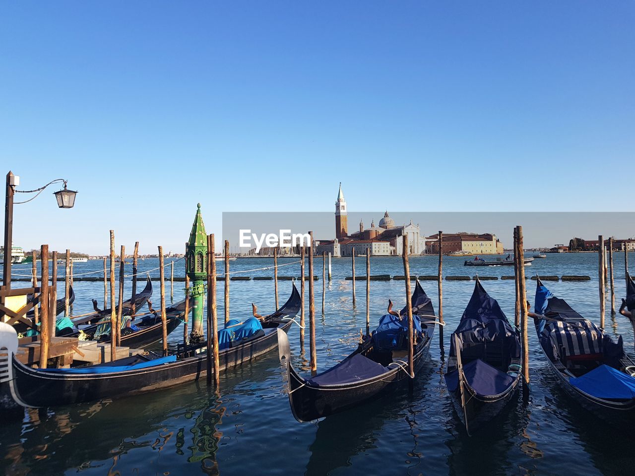 Boats moored in canal against clear blue sky