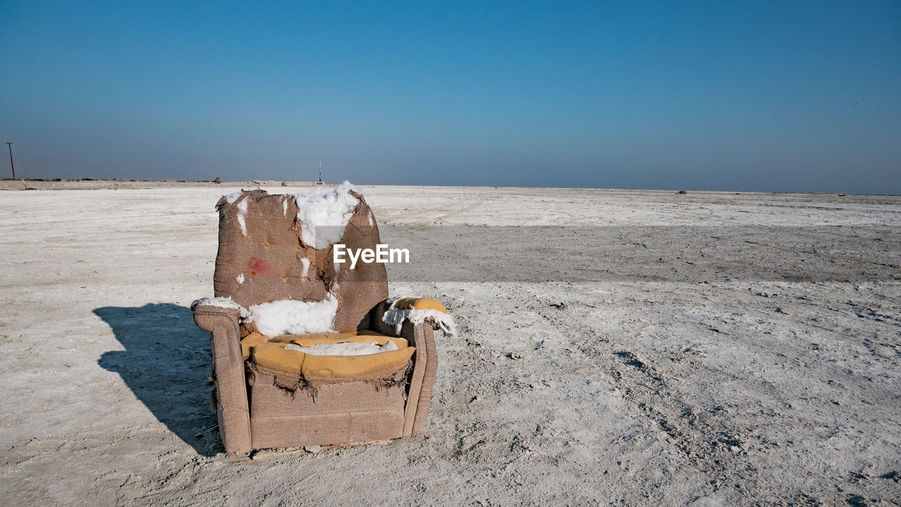 Couch on a salt flat against clear sky