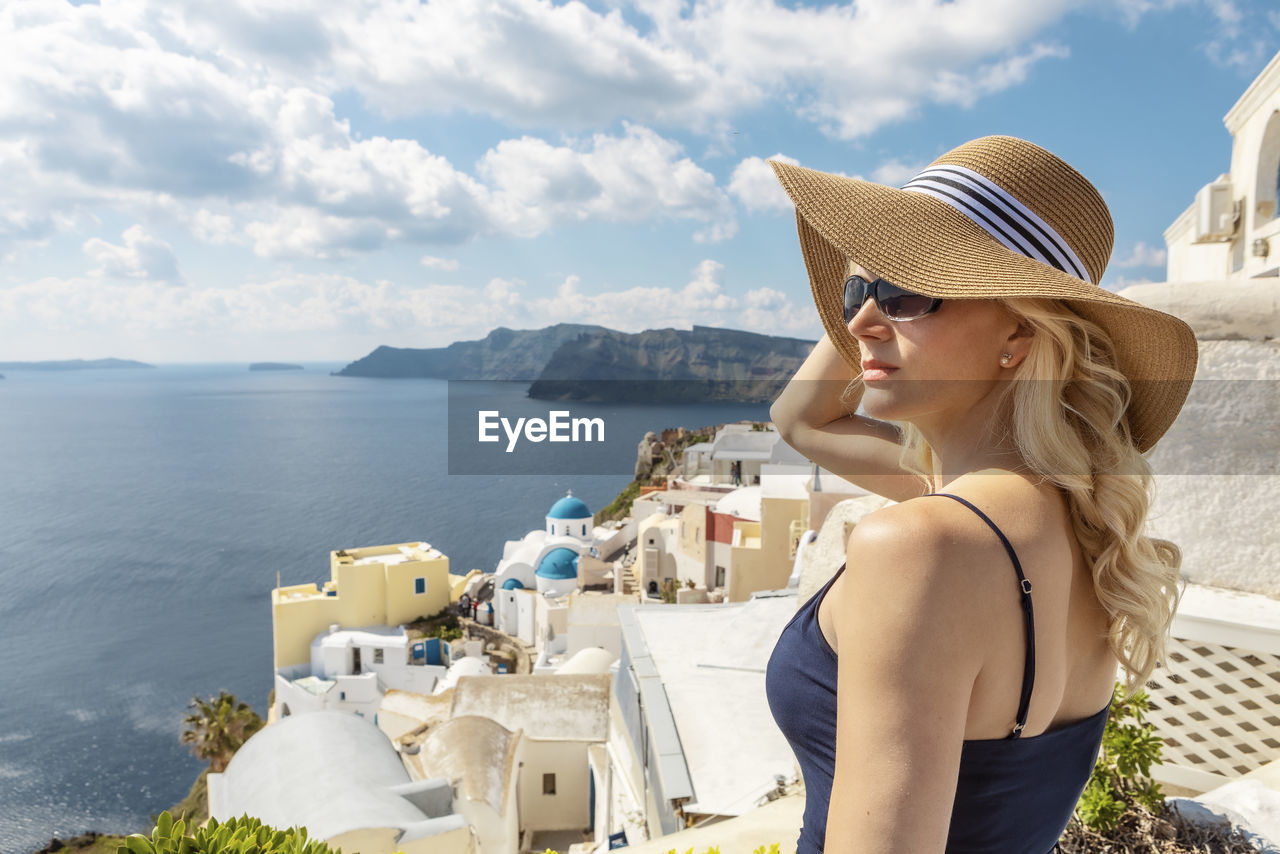 YOUNG WOMAN WEARING HAT AGAINST SEA