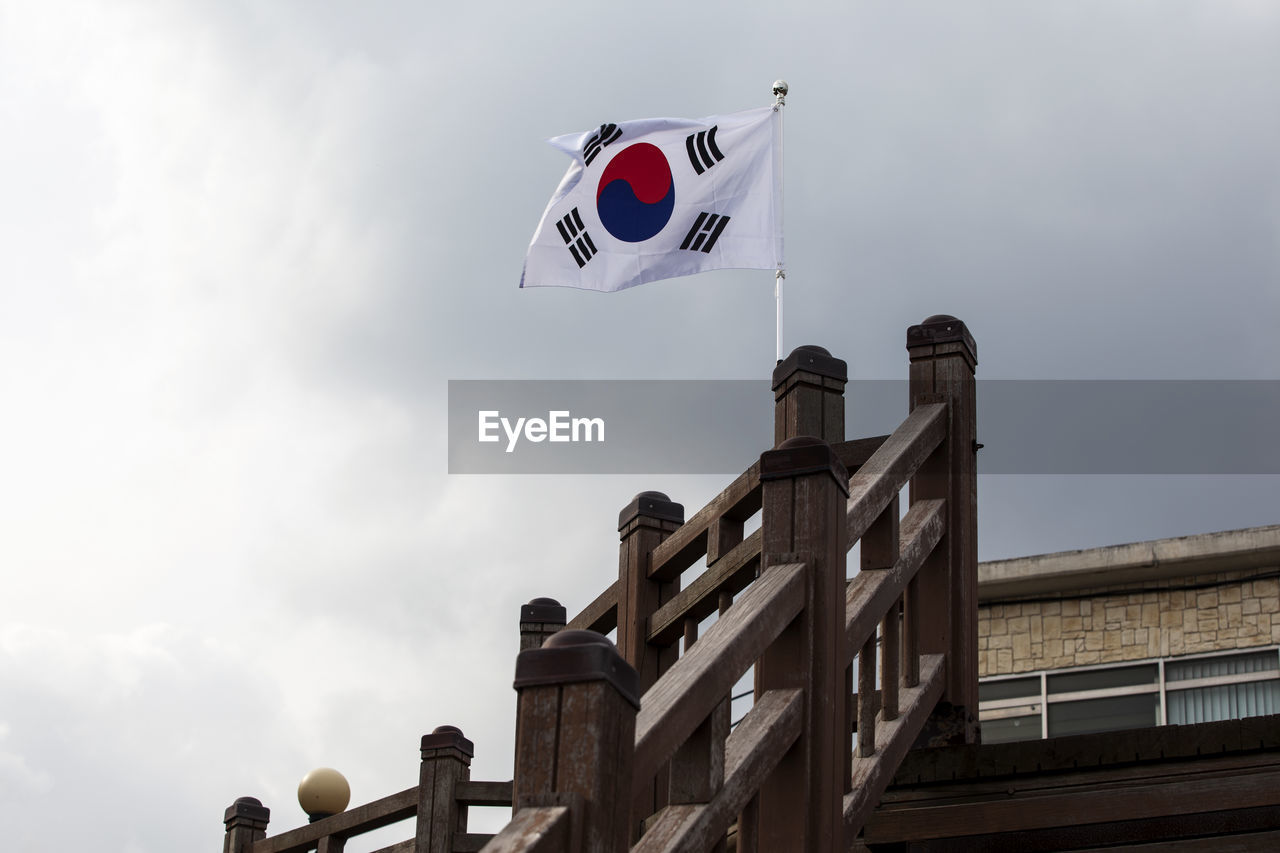 Low angle view of south korean flag on wooden railing at observation point